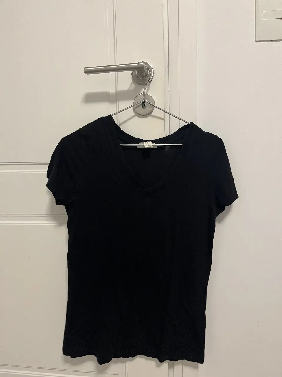 Remera negra de manga corta con cuello en V, ideal para un look casual y versátil. Perfecta para combinar con jeans o pantalones de vestir.