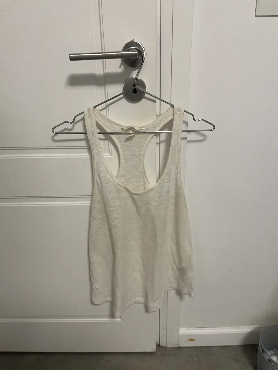 Musculosa blanca de tela liviana, ideal para el verano. Con espalda deportiva y escote redondo. Perfecta para un look casual y fresco.