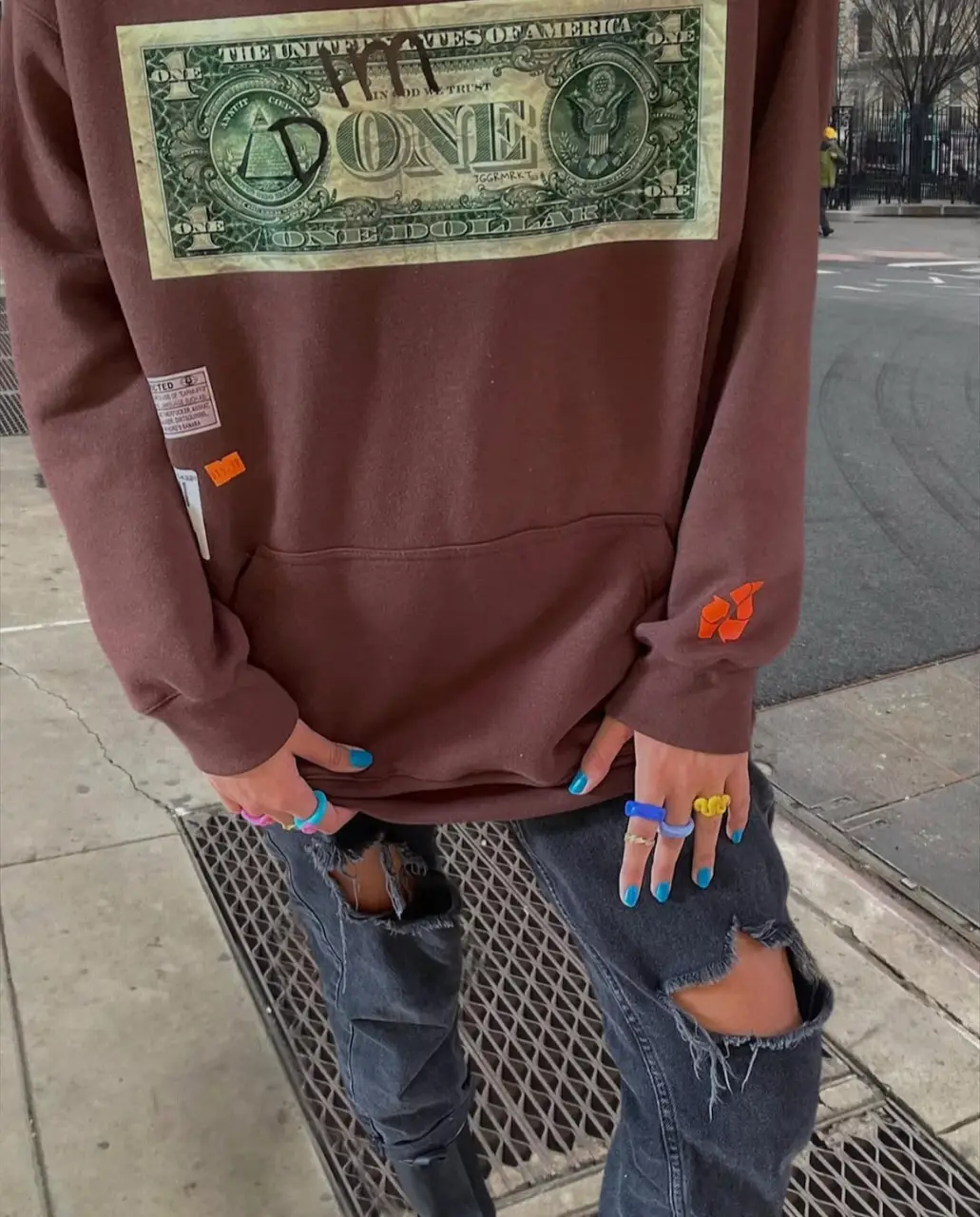 Buzo canguro marrón con estampado de billete de dólar en el frente. Estilo streetwear, ideal para un look casual y moderno. El mismo diseño en otro color cuesta $56.900 nuevo. Este ya no se consigue. 