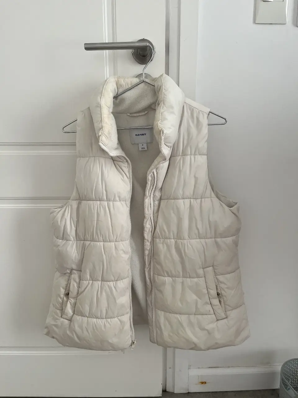 Chaleco acolchado de color crudo, ideal para el invierno. Cuenta con cierre y bolsillos. Marca Old Navy, talle M.