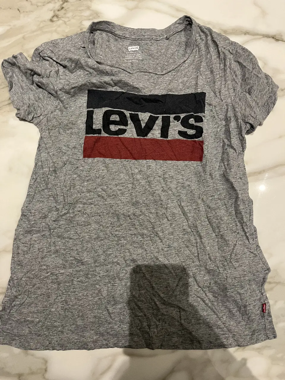 Remera de hombre de la marca Levi's, de color gris con estampado del logo en negro, rojo y blanco. Ideal para un look casual y cómodo.