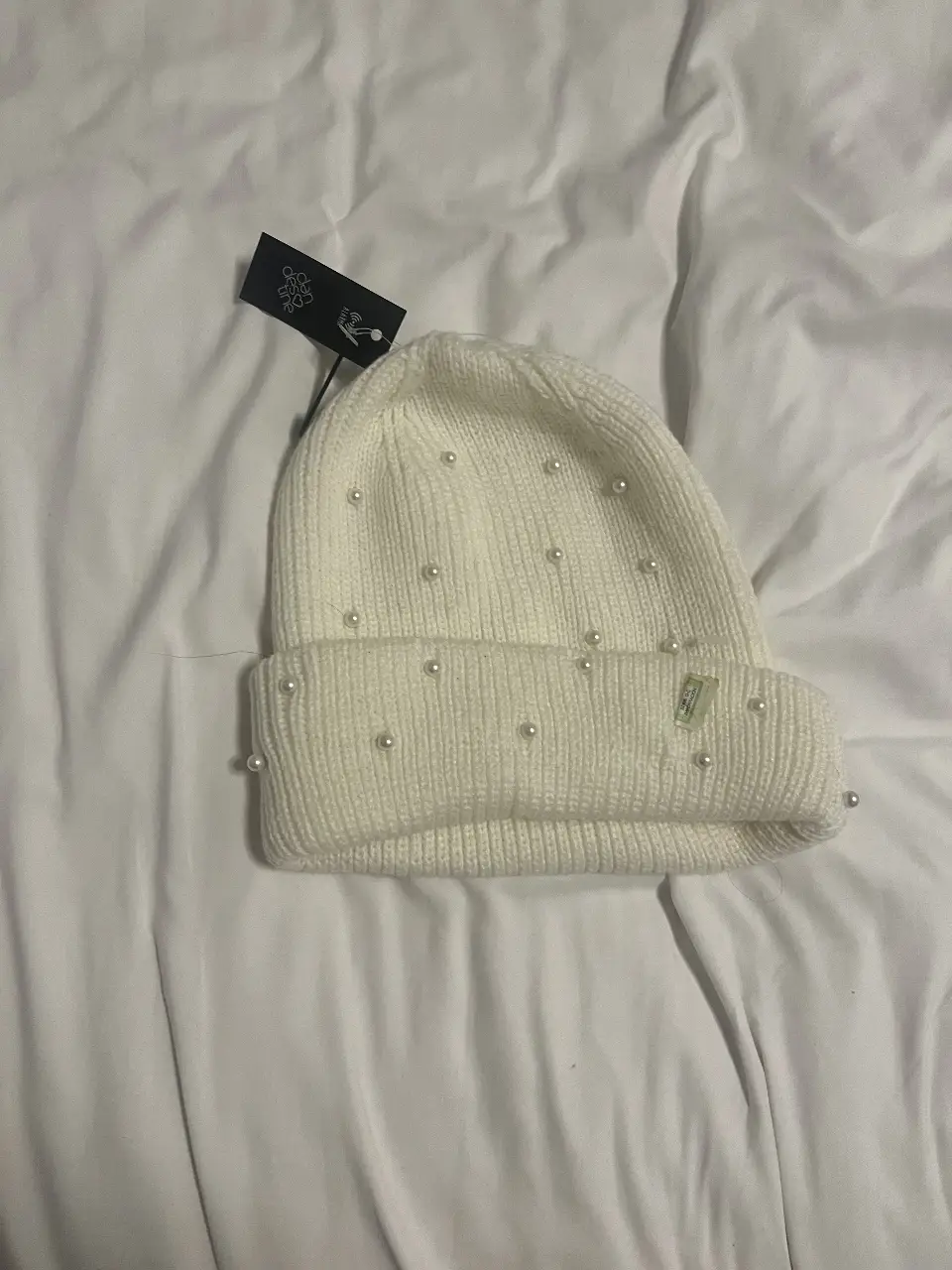 Gorro tejido de color blanco con perlas decorativas. Ideal para un look elegante y abrigado en invierno. Perfecto para combinar con diferentes outfits.