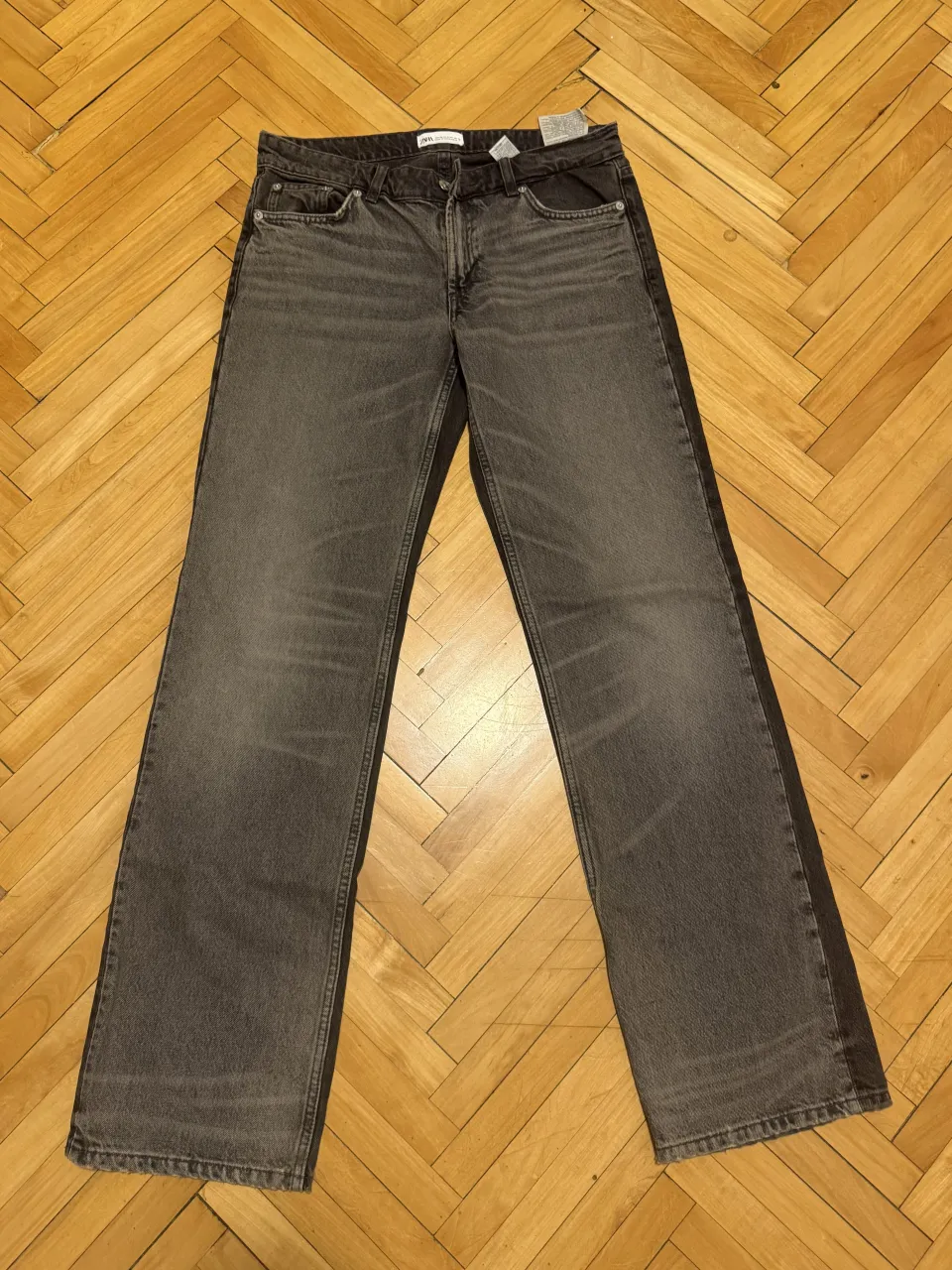 Jeans de tiro medio con detalles de desgaste y dos tonos de gris. Cierre y botón.