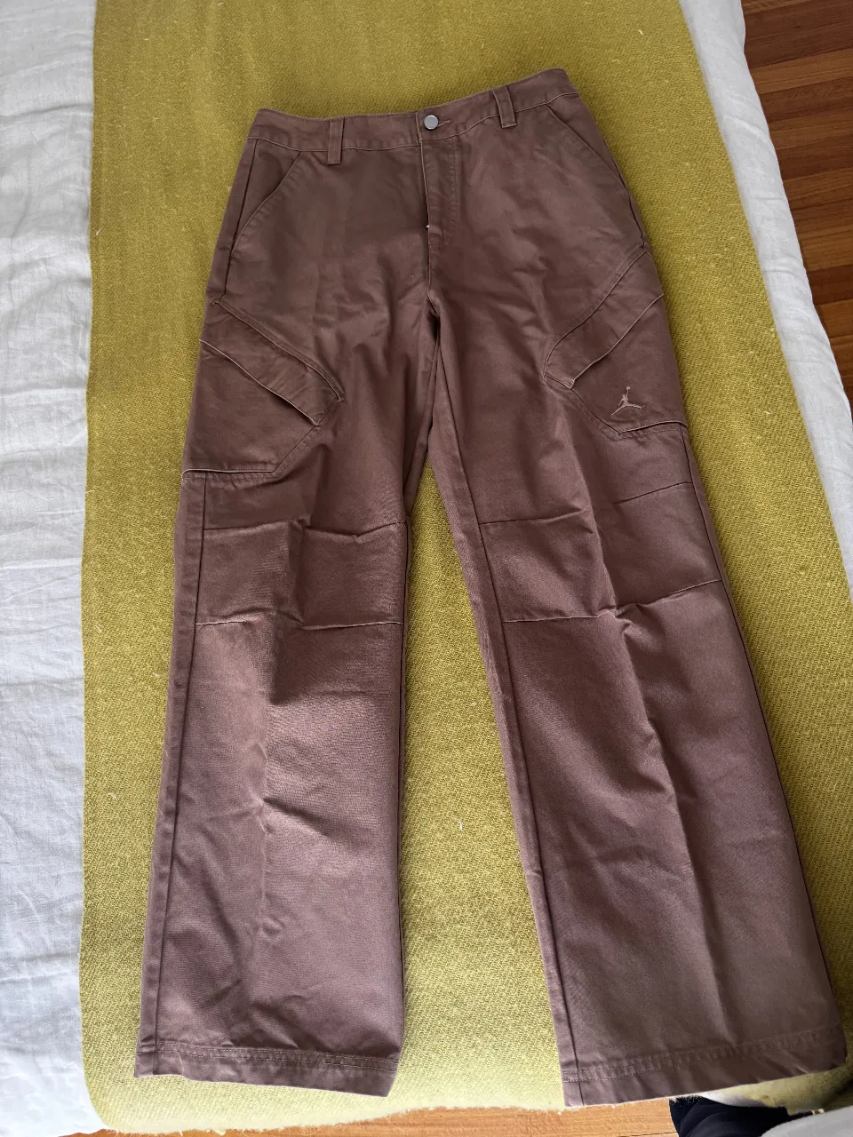 Pantalón cargo marrón de hombre, con el logo de Jordan bordado. Corte estándar, con bolsillos laterales y traseros. Ideal para un look casual y urbano.