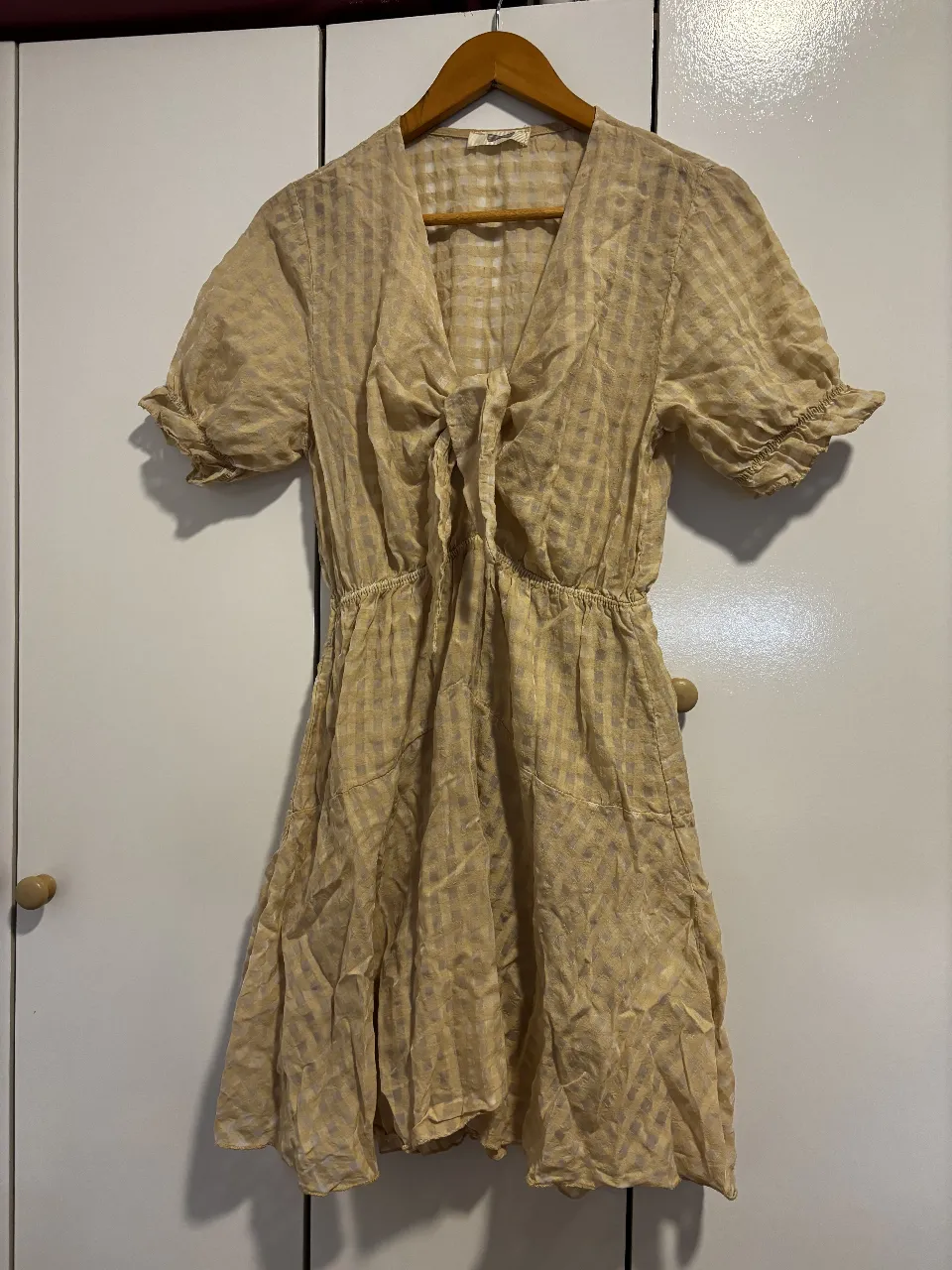 Vestido mini de mujer, color crudo con diseño a cuadros. Corte en la cintura y mangas cortas con volados. Ideal para un look casual y fresco.