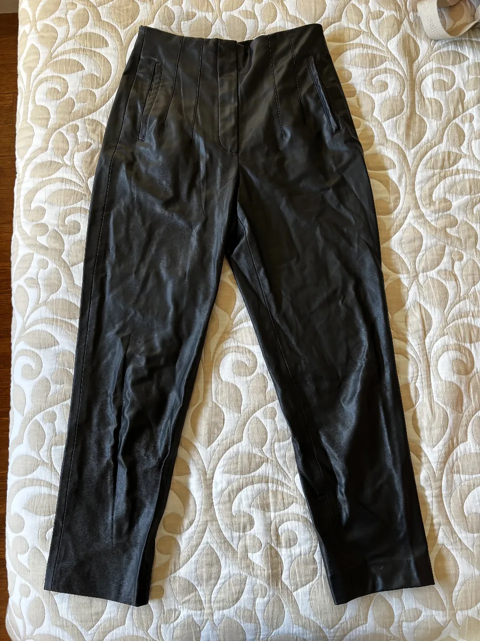 Pantalón sastrero de cuero sintético negro, tiro alto, con detalles de costuras y bolsillos. Ideal para un look elegante y moderno. muy buen estado