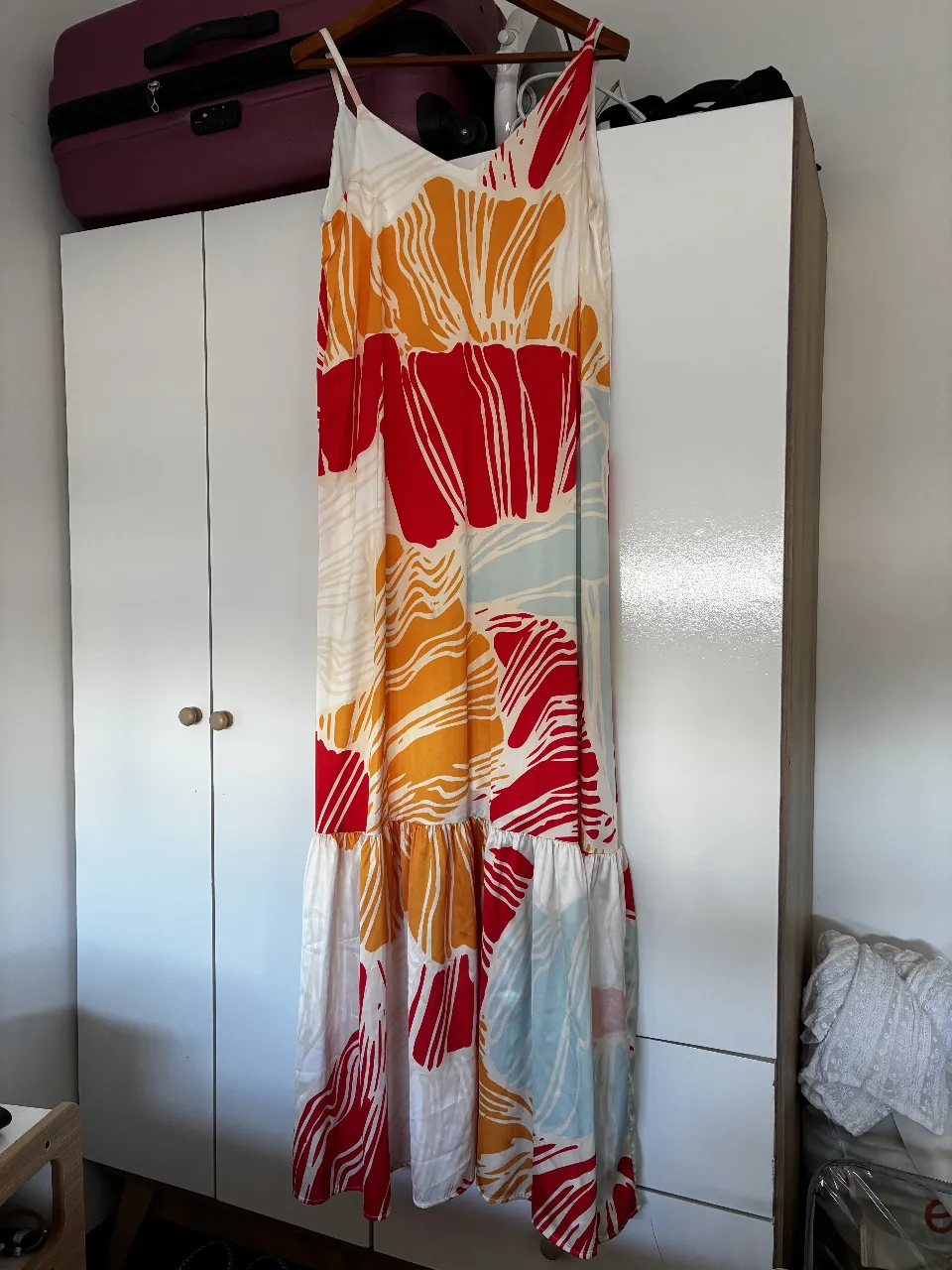 Vestido largo de mujer con estampado floral en tonos rojo, naranja y blanco. Diseño con tirantes finos y volados en la parte inferior. Ideal para un look fresco y veraniego.