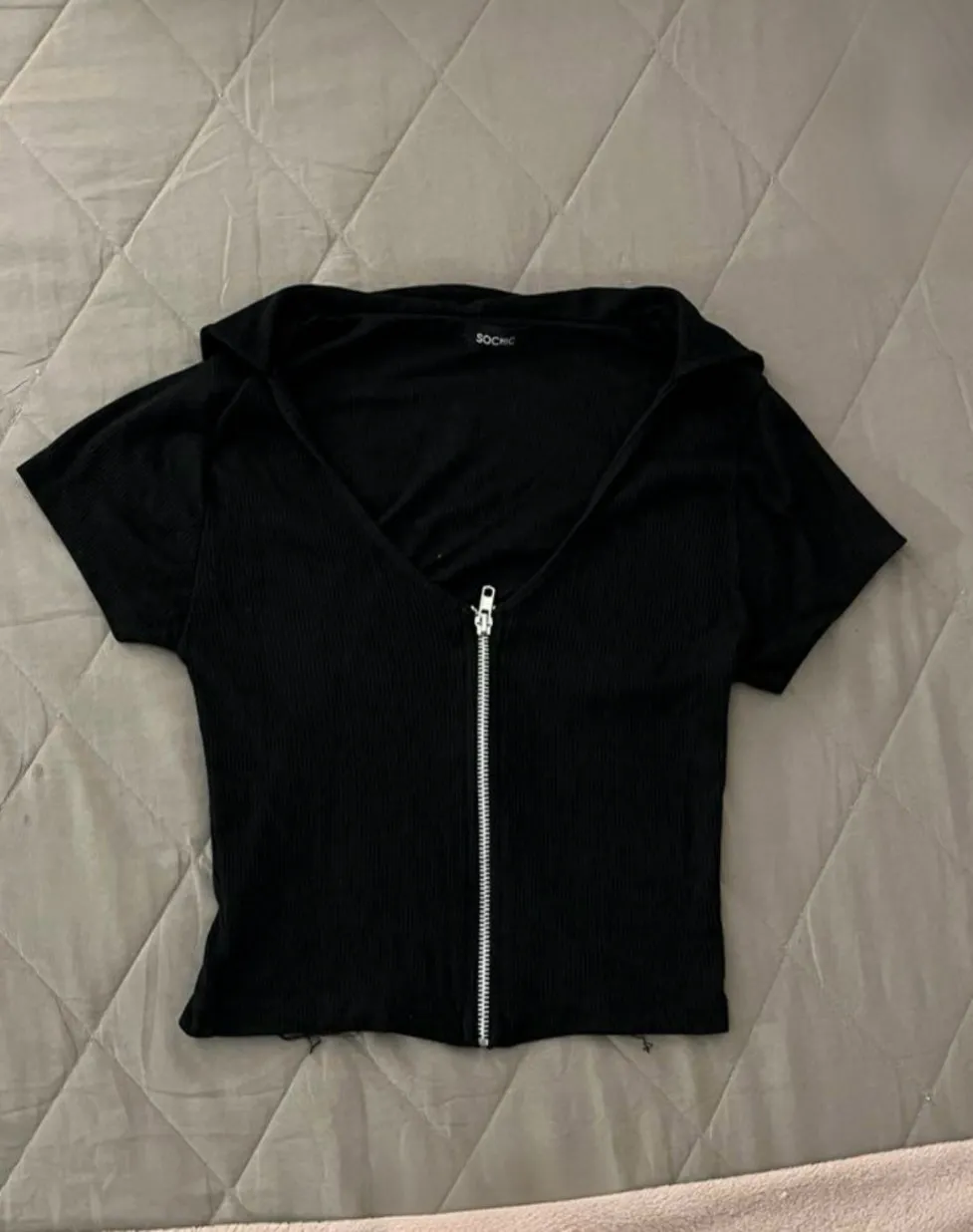 Top negro con cierre frontal y cuello. Ideal para un look casual y moderno. Marca SoChic.