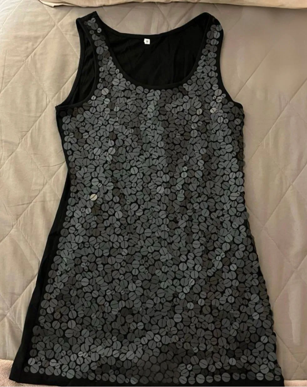 Vestido mini de mujer, sin mangas, con diseño de lentejuelas grises en forma de granos de café sobre fondo negro. Ideal para una salida o fiesta.