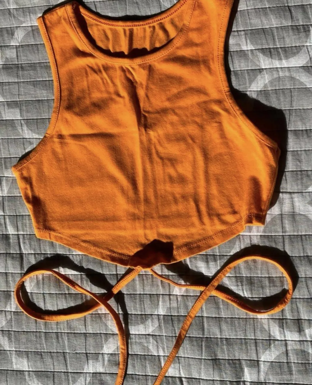 Top corto de color naranja con tiras para atar en la espalda. Ideal para un look casual y fresco.