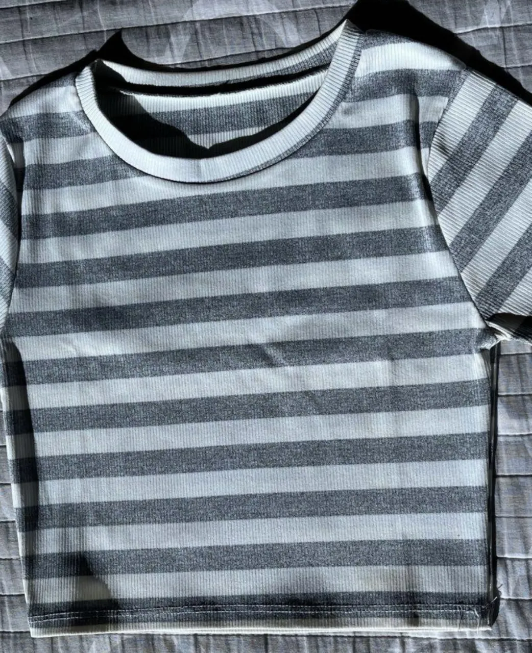 Remera a rayas gris y blanca, de corte ajustado y manga corta. Ideal para un look casual y moderno.