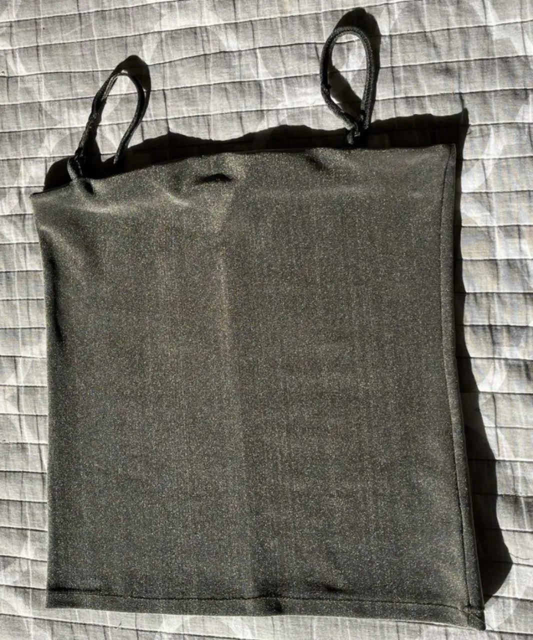Top negro con breteles finos. Ideal para usar en verano o para combinar con otras prendas. Diseño simple y versátil.