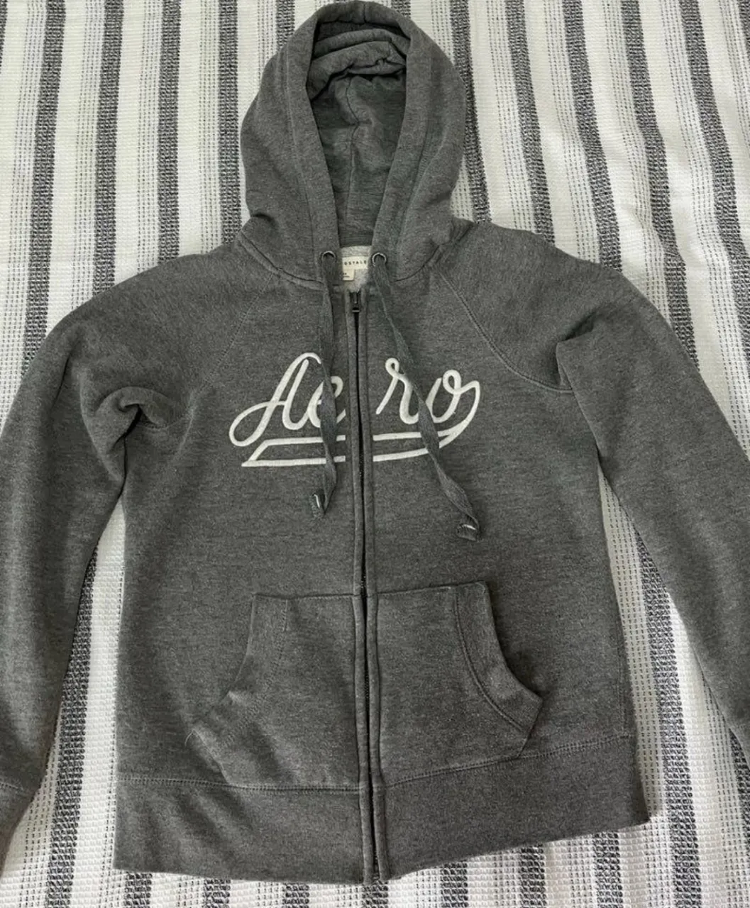 Buzo con cierre y capucha de la marca Aeropostale, color gris. Talle XS. Ideal para un look casual y cómodo.