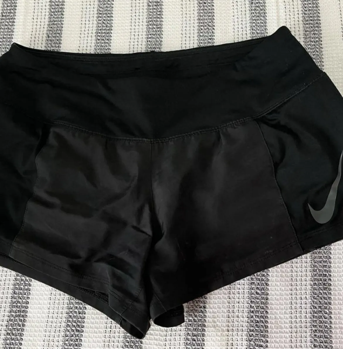 Short deportivo negro de la marca Nike, con cintura elastizada y detalle "JUST DO IT." en la parte superior trasera. Ideal para running y entrenamientos.