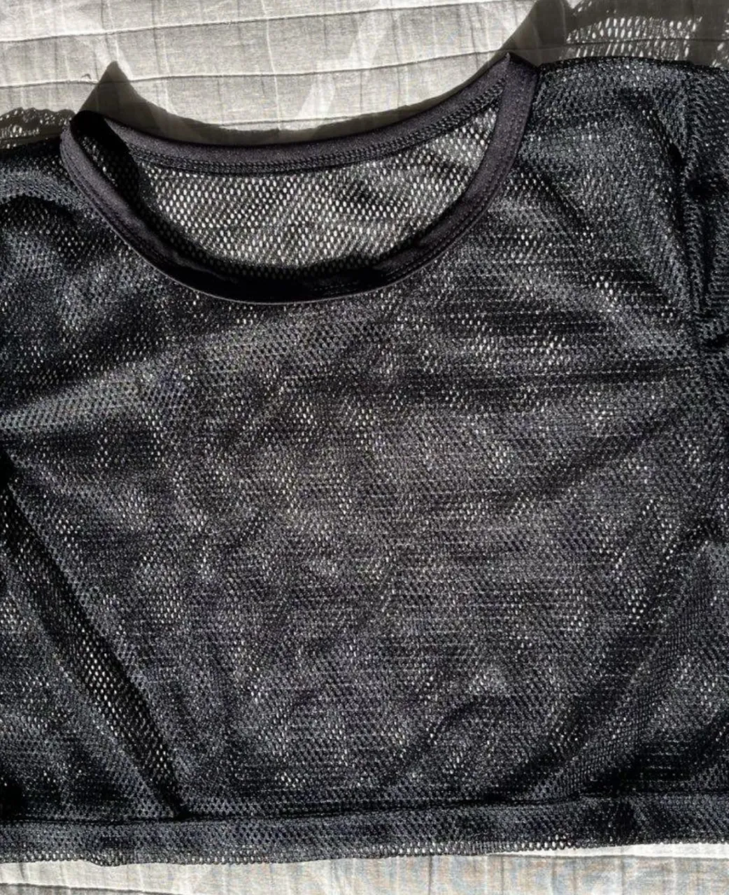 Top de red negro, ideal para usar sobre otras prendas. Perfecto para un look moderno y audaz.