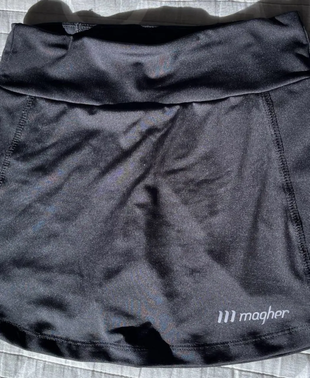 Pollera deportiva negra de la marca magher, con short interno. Posee un bolsillo con cierre en la cintura.