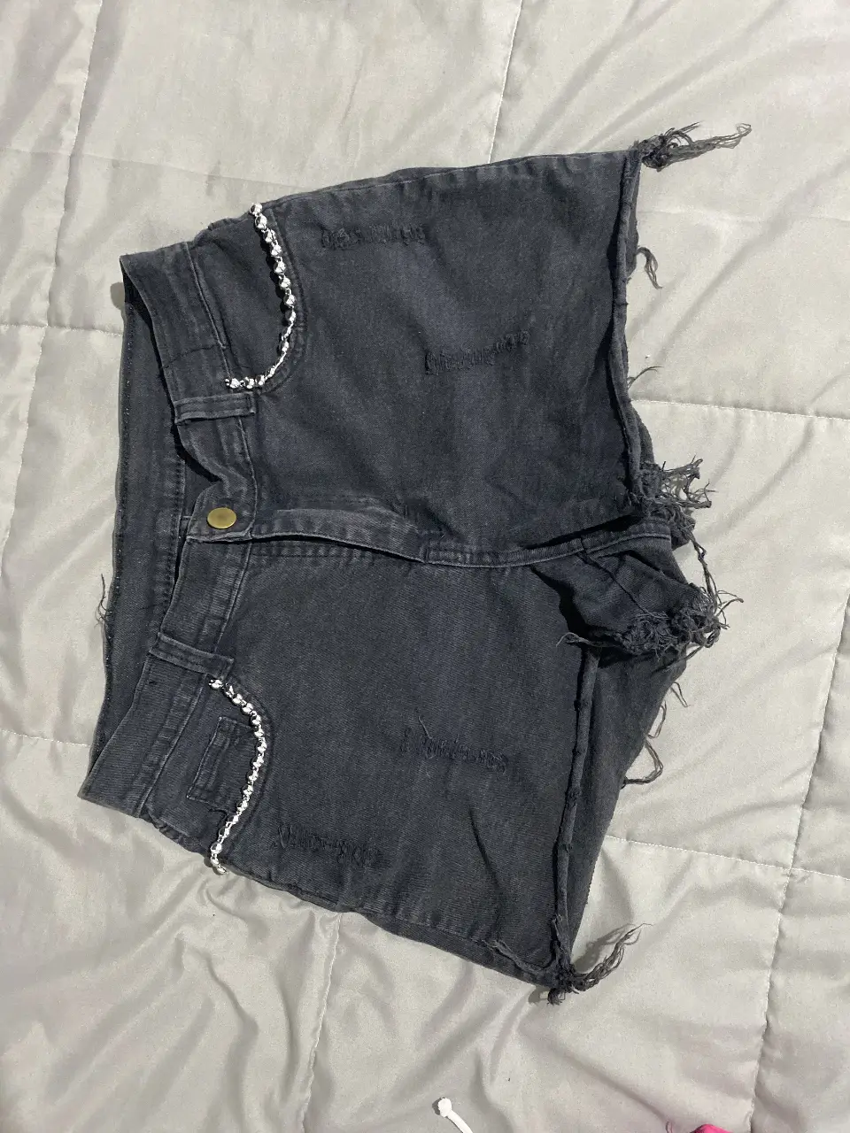 Short de jean negro con detalles rotos y bordados blancos. Ideal para un look casual y moderno.