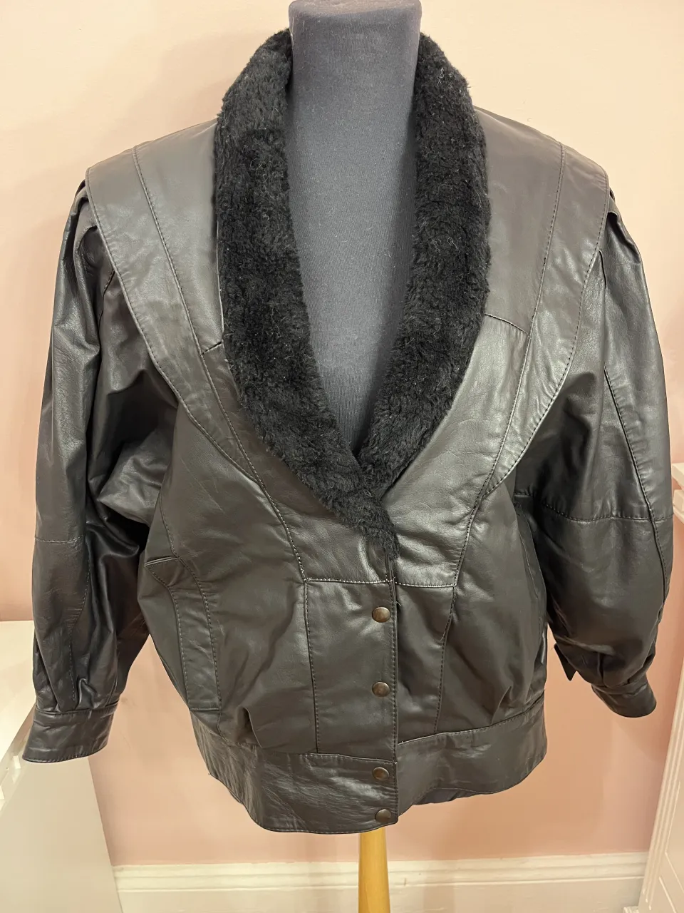 Campera de cuero negra con cuello de piel. Cierre delantero con botones y bolsillos laterales.