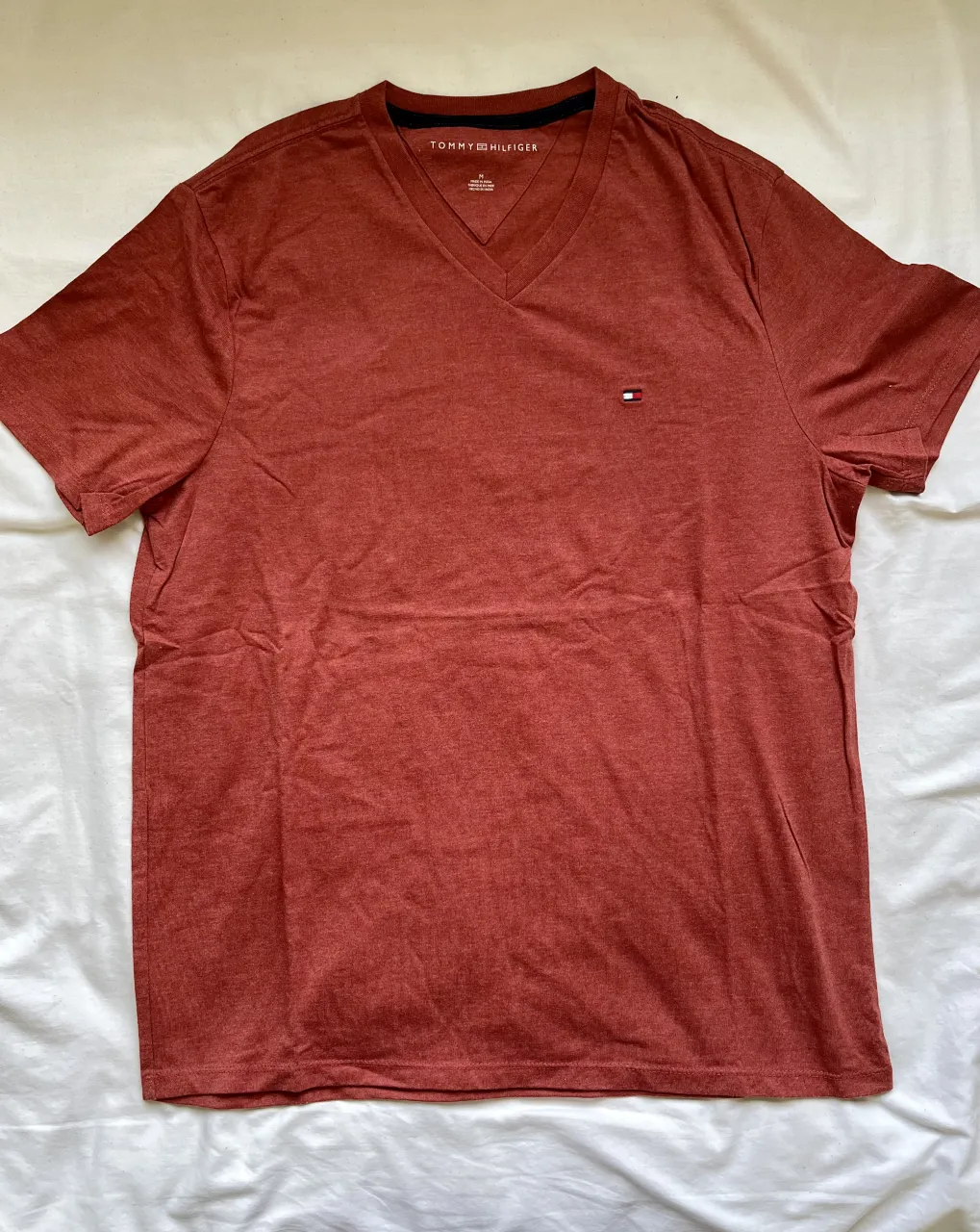 Remera de hombre Tommy Hilfiger, color ladrillo, talle M. Escote en V, manga corta. Ideal para uso casual y diario.