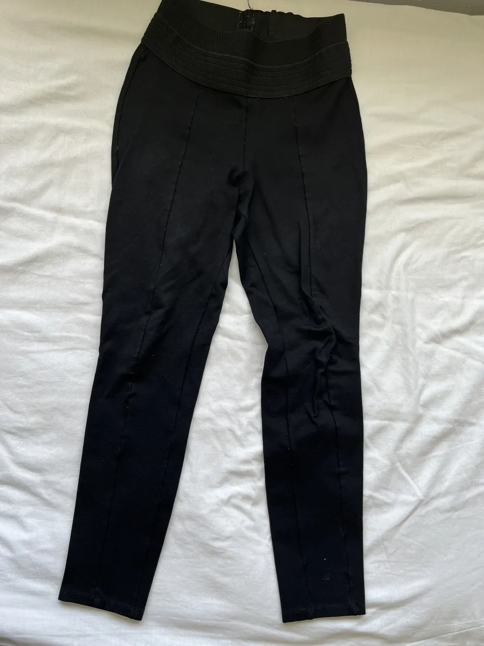 Pantalón negro tiro alto con elástico en la cintura y detalles de costura. Un básico súper cómodo y versátil para tu día a día.