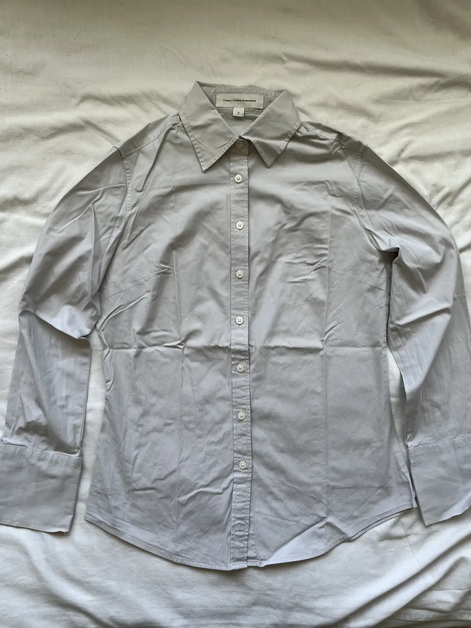 Camisa de vestir manga larga, color gris claro. Posee botones blancos al frente y en los puños. Ideal para un look elegante o casual.