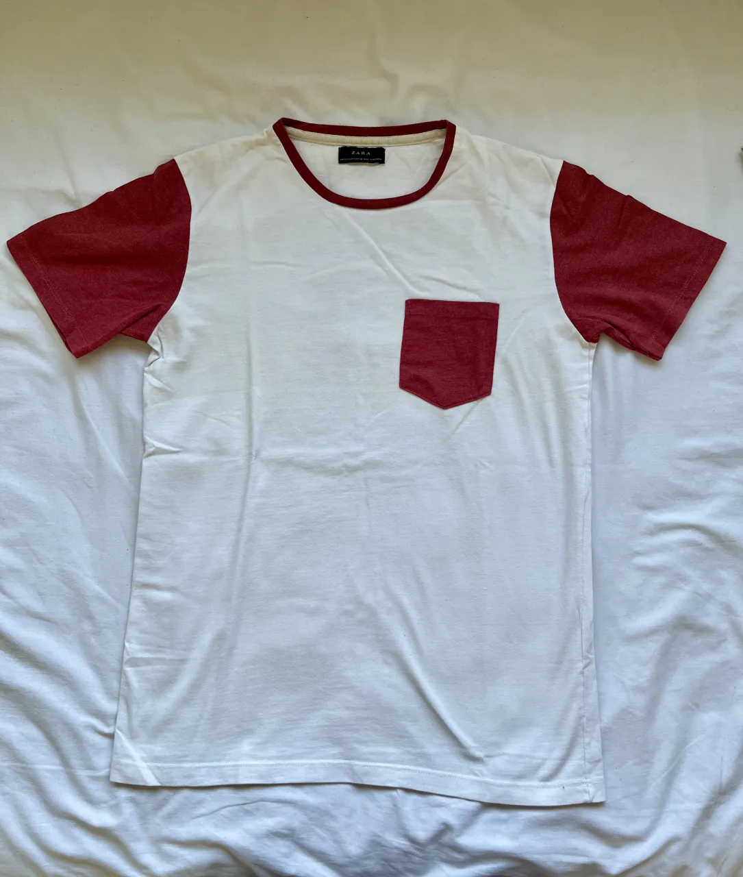 Remera blanca con mangas y bolsillo en color rojo. Estampado en la espalda "FORGET THE TIME" en color rojo. Cuello redondo.