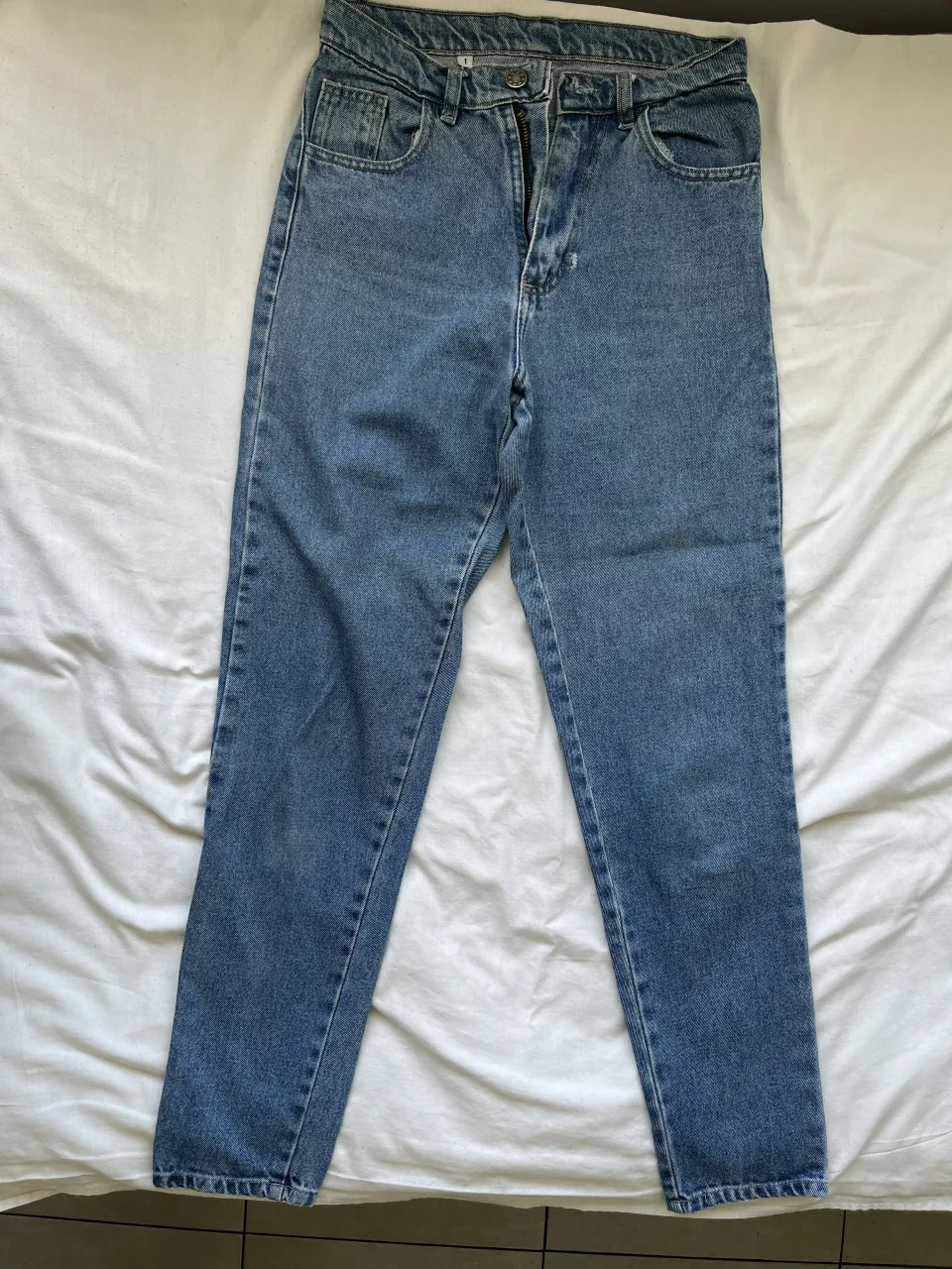 Jeans tiro alto, corte recto, color azul clásico. Perfectos para un look casual y moderno. Ideales para combinar con remeras, buzos o camisas.