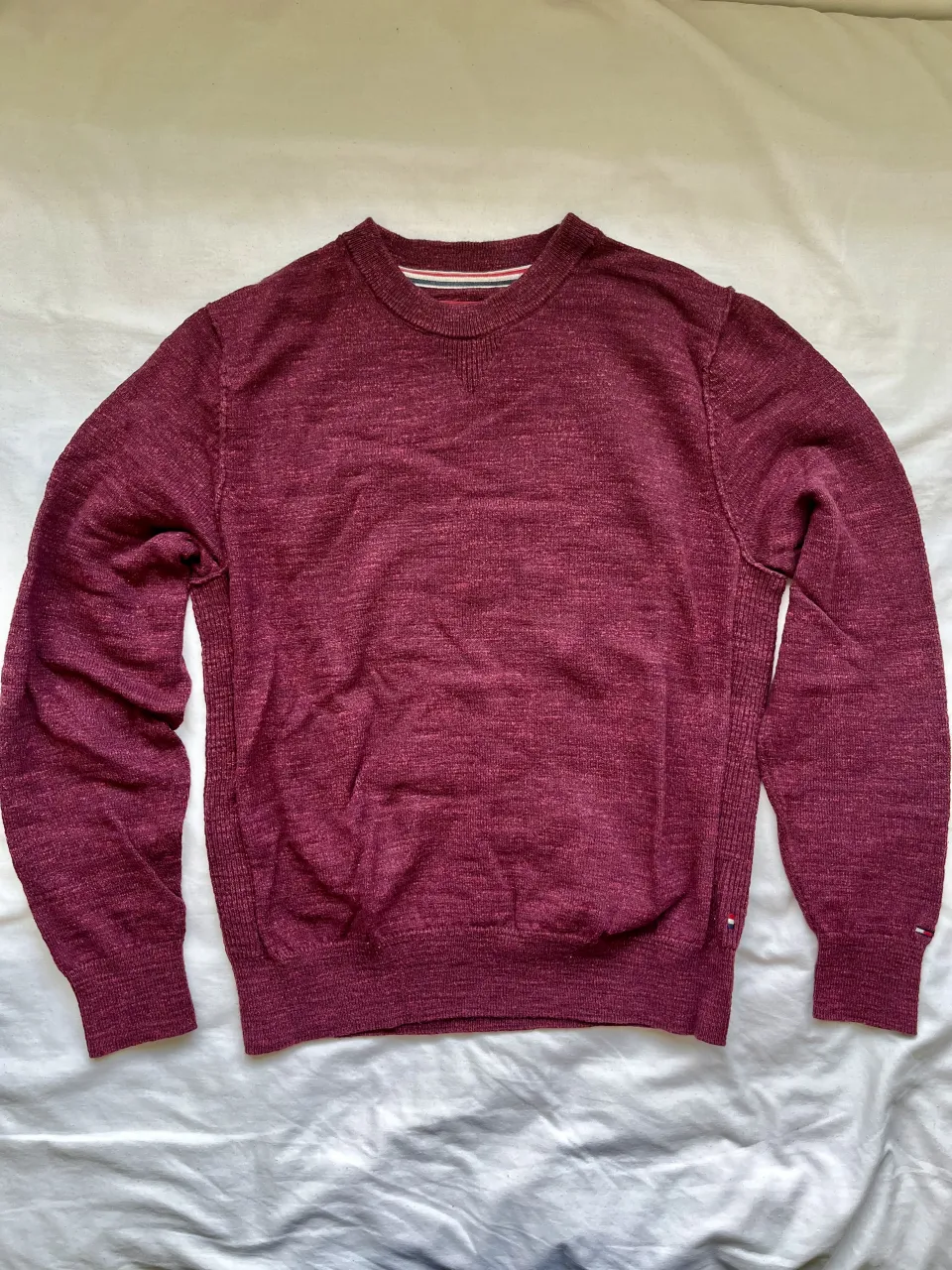 Pulóver de tejido fino en color bordó, con cuello redondo y detalles de costura en los laterales. Ideal para un look casual y cómodo.