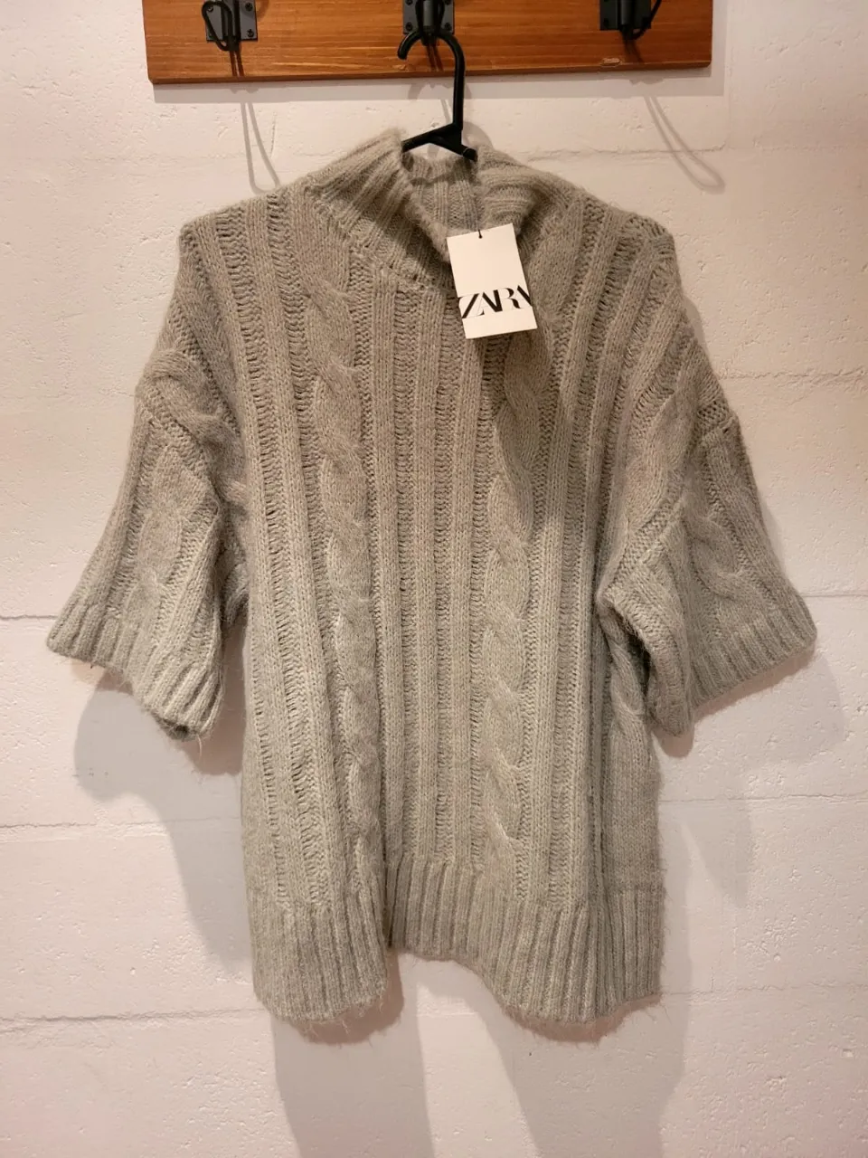 Sweater de lana tejido con trenzas y cuello alto. Manga corta, ideal para un look canchero y abrigado en días frescos. Combina perfecto con jeans o pantalones de vestir.