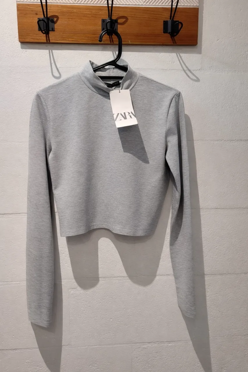 Remera gris de manga larga con cuello alto.