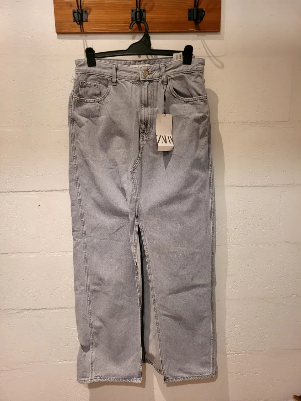 Pollera larga de jean gris, tiro alto, con tajos laterales. Un básico moderno para cualquier look.