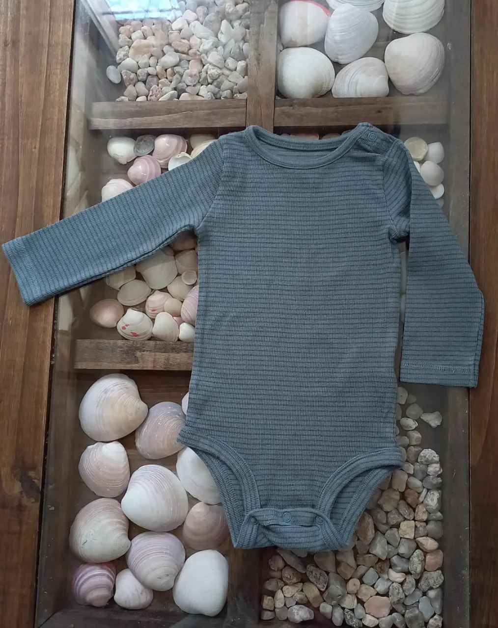 Body de manga larga a rayas grises. Tiene broches en la parte inferior para facilitar el cambio.