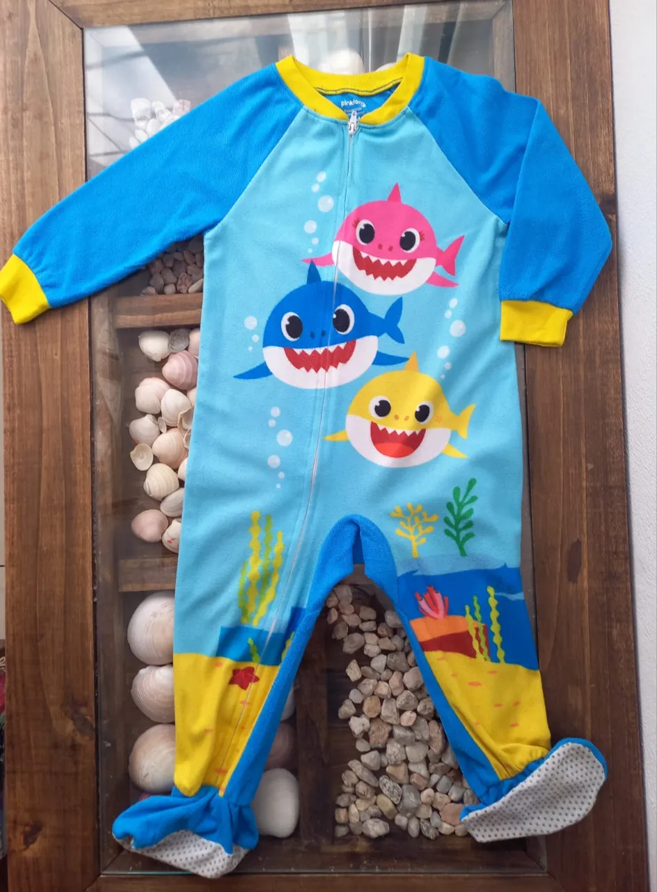 Enterito de pijama infantil con estampa de tiburones de la serie Baby Shark. Tiene cierre al frente y puños en mangas y tobillos.