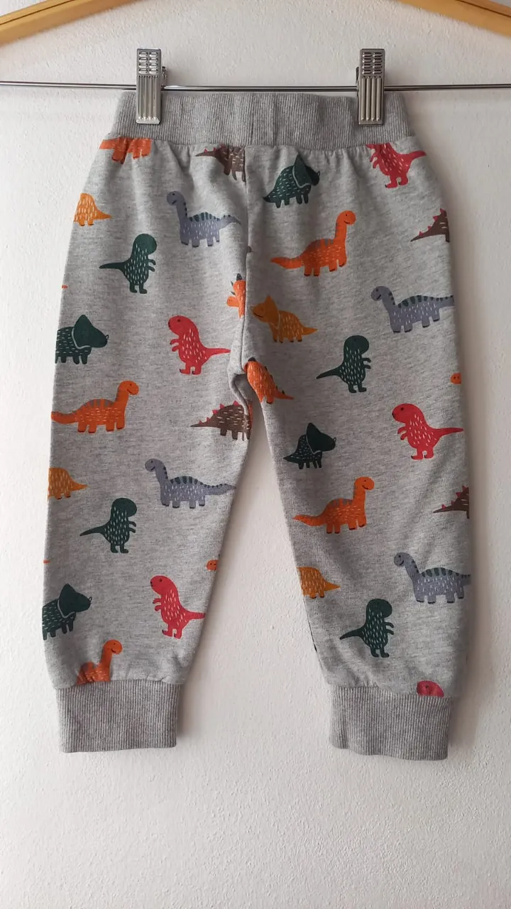 Pantalón de algodón gris con estampa de dinosaurios de colores. Cintura elastizada y puños en los tobillos.