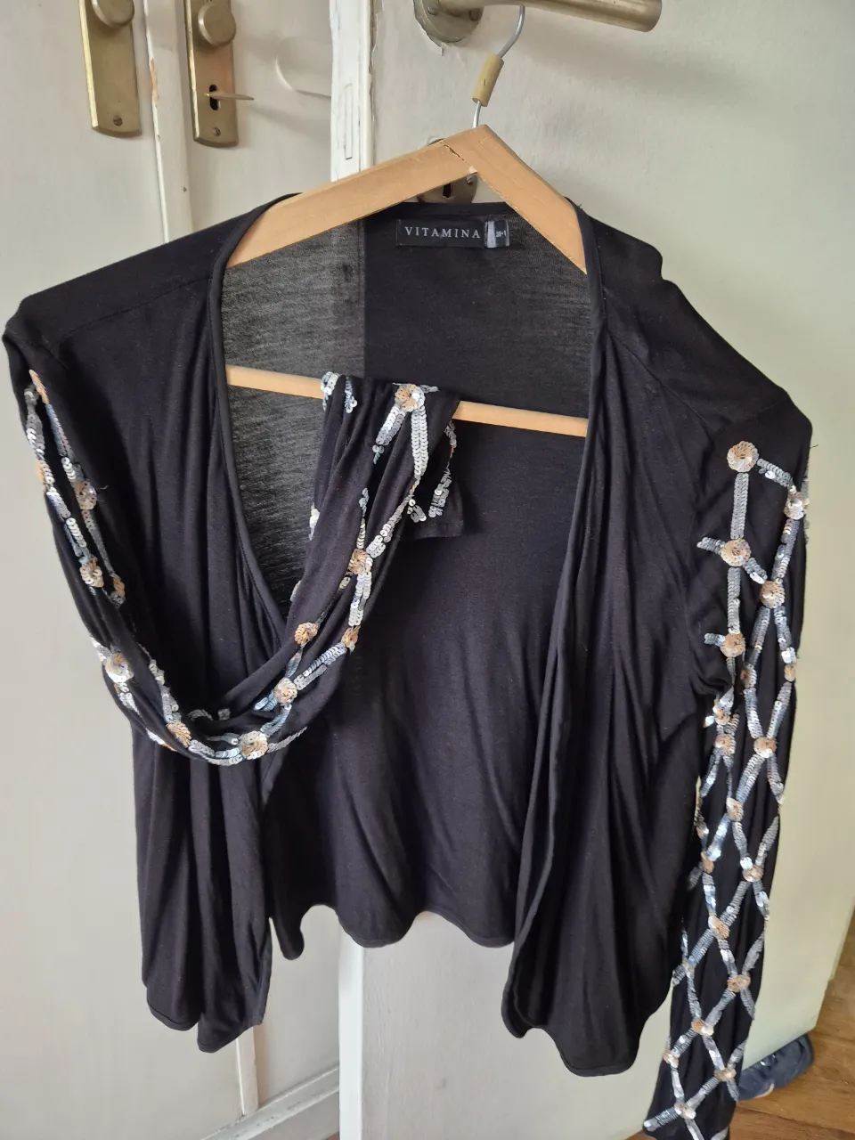 Saco liviano negro con mangas adornadas con lentejuelas plateadas y rosas  en un diseño único. Ideal para darle un toque de brillo a cualquier outfit.