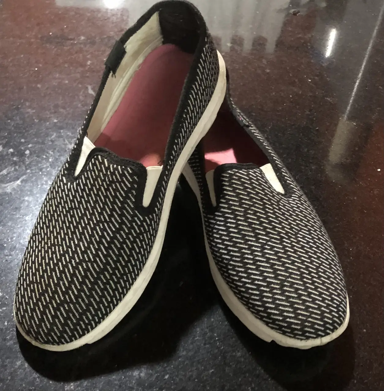 Zapatillas slip-on para mujer, con diseño tejido en blanco y negro. Suela blanca y detalle en el empeine. Ideales para un look casual y cómodo.