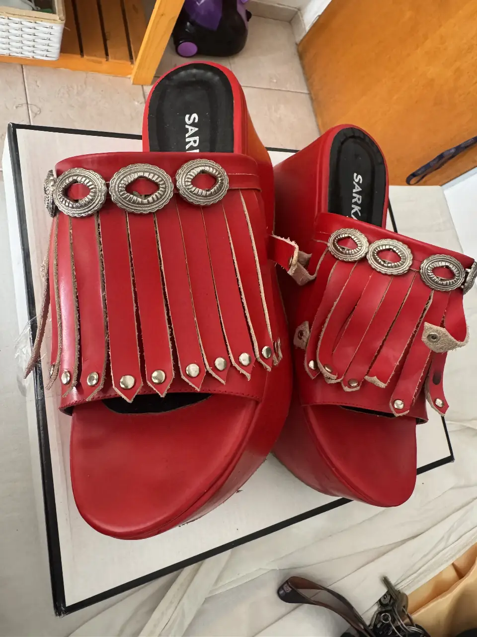 Sandalias rojas con plataforma y detalles de flecos y hebillas plateadas. Ideales para un look audaz y moderno.