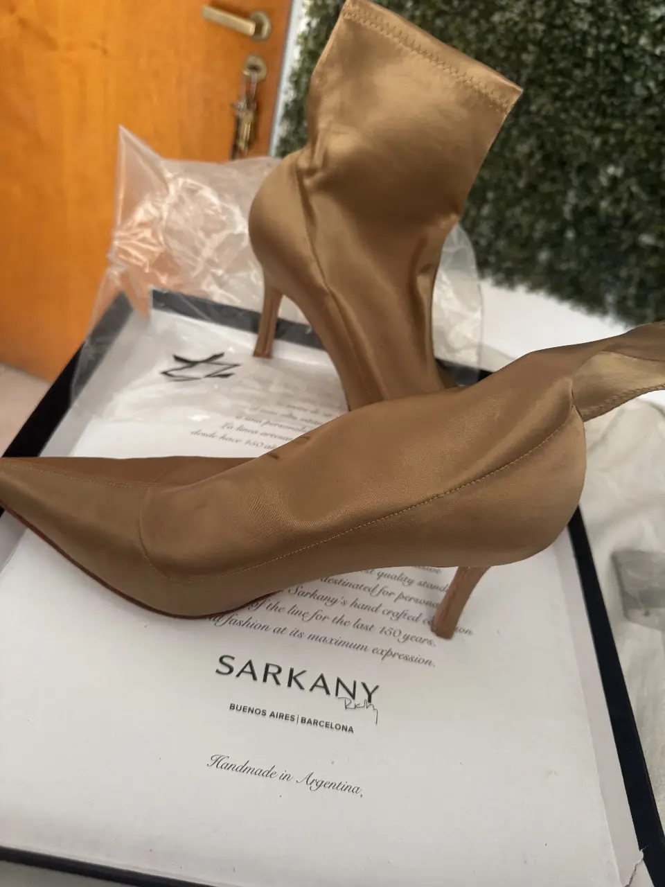 Botinetas de taco alto color dorado, de la marca Sarkany. Confeccionadas en satén, ideales para eventos formales o fiestas.