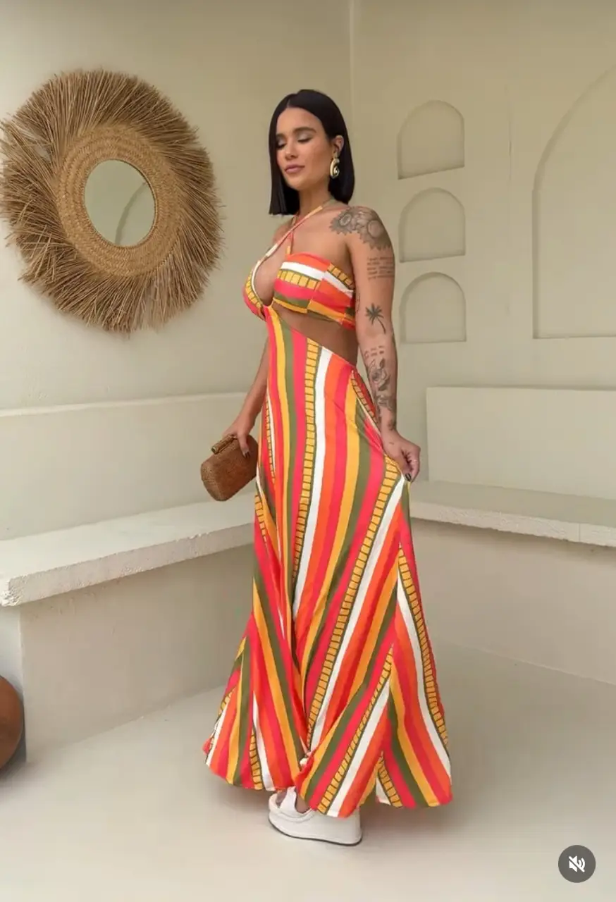Vestido largo con estampado a rayas en tonos naranja, amarillo, verde y blanco. Diseño con corte en la cintura y abertura lateral, ideal para un look fresco y moderno.