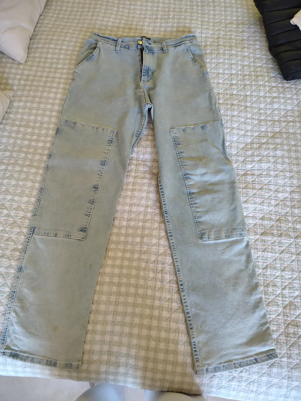 Jean de tiro medio, color celeste claro, con parches de tela en la zona de las rodillas y costuras visibles. Posee bolsillos delanteros y traseros.