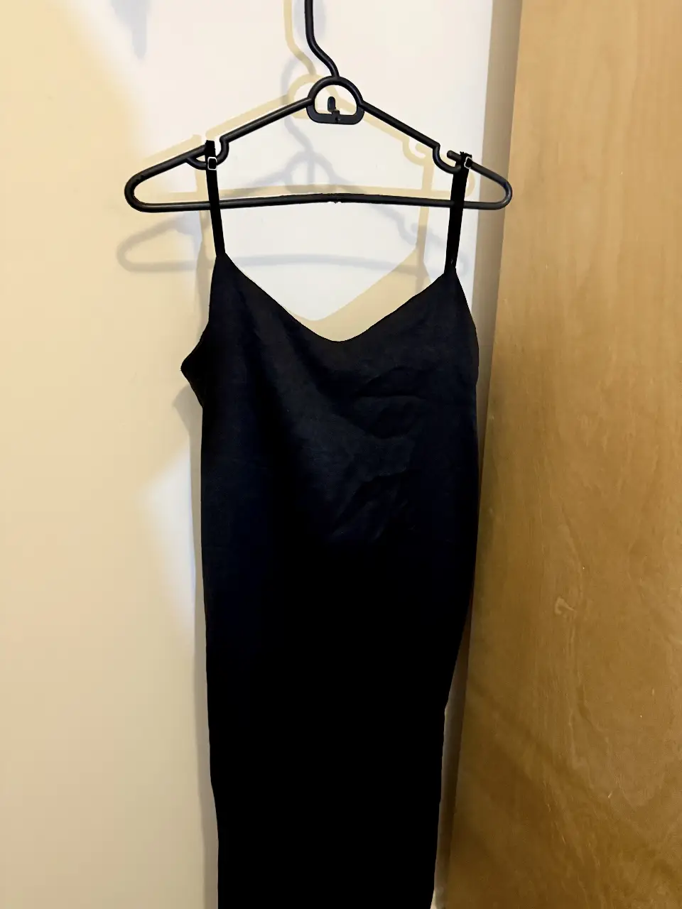 Vestido negro con tiras finas y escote en V, ideal para un look elegante y versátil.