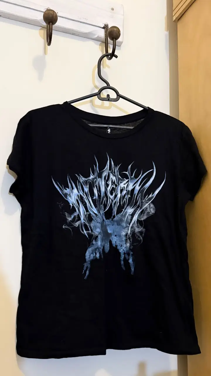 Remera negra con estampado de diseño gótico en la parte delantera. Ideal para un look rocker o streetwear.