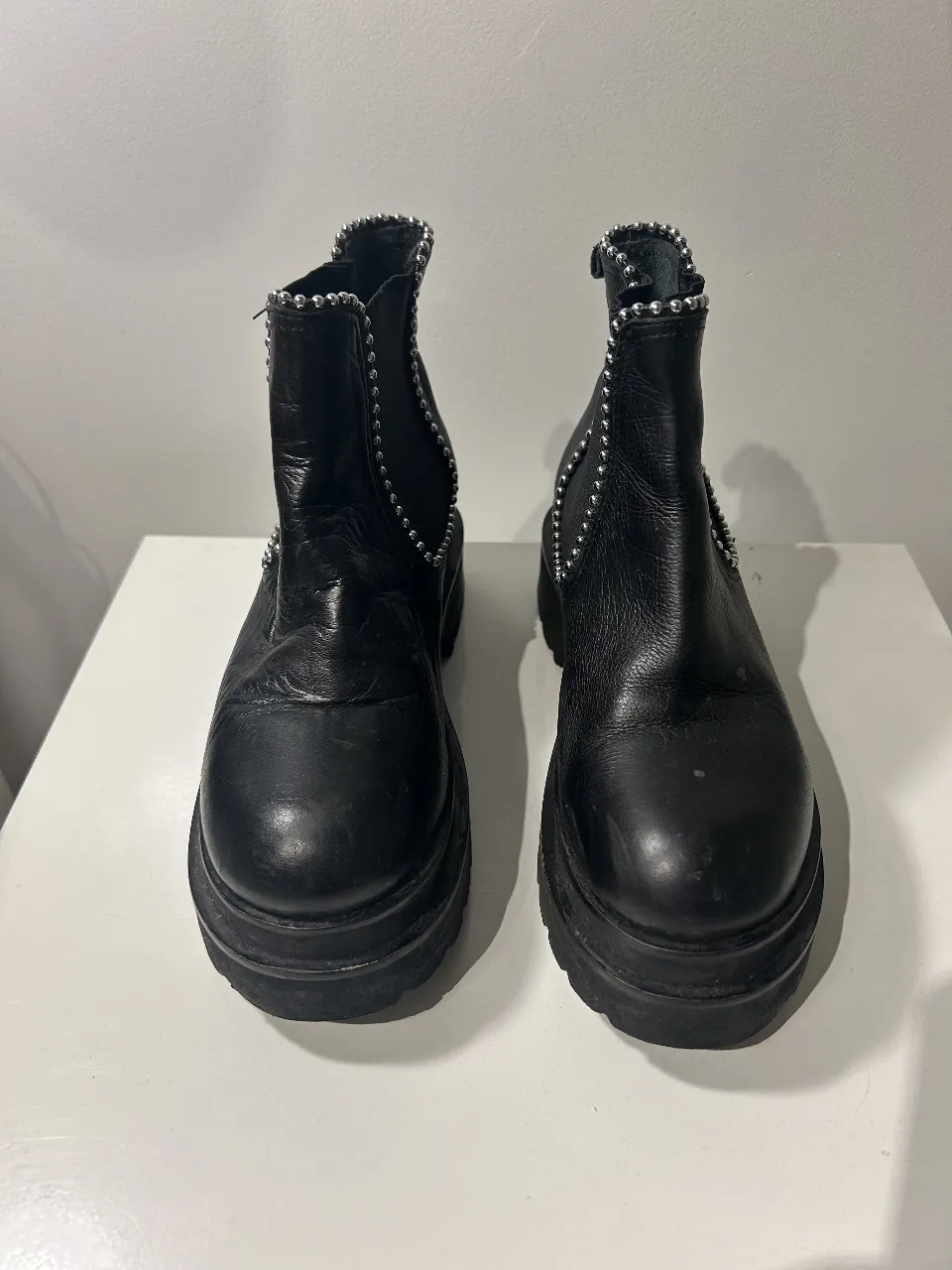 Botas de cuero negrascon detalles de tachas plateadas en el borde superior. Suela alta  y diseño moderno.