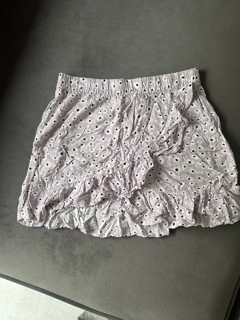 Pollera mini con estampado floral en tonos lilas y blancos. Diseño con volados y cintura elastizada. Marca: H&M