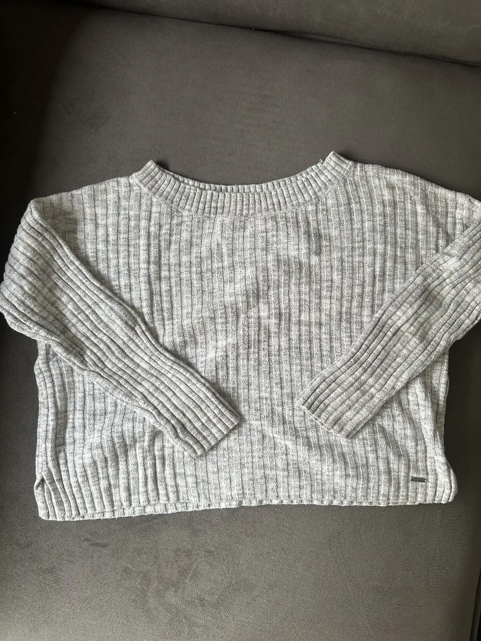 Sweater gris de la marca Hollister, talle XS. Tejido de punto acanalado, ideal para un look casual y cómodo. Perfecto para el día a día.
