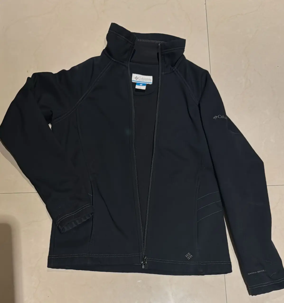 Campera deportiva Columbia negra, con cierre y cuello alto. Ideal para actividades al aire libre o uso diario. Tiene bolsillos con cierre 