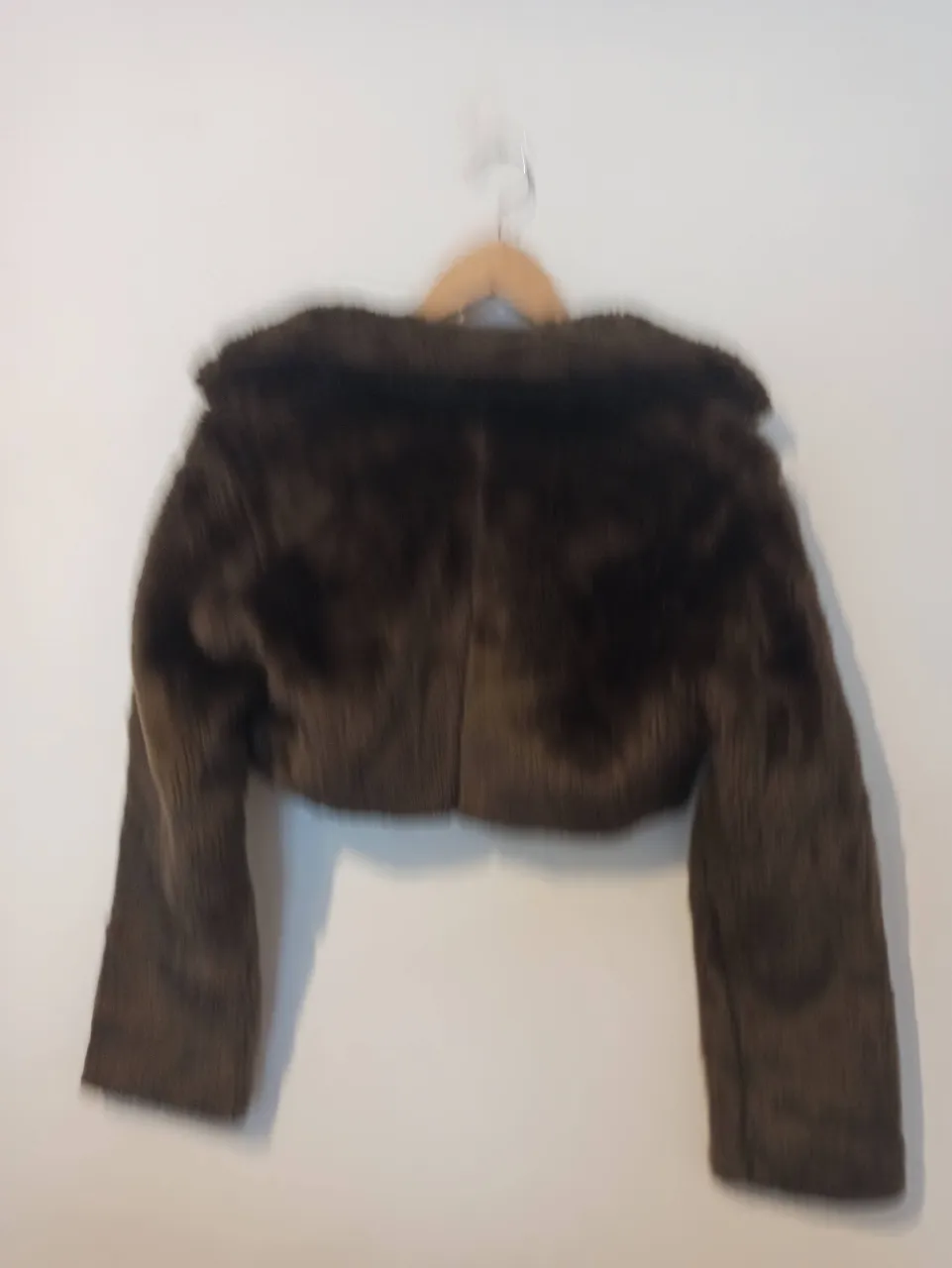 Abrigo corto de pelo sintético súper suave y calentito. Ideal para darle un toque chic a cualquier look. Tiene un diseño moderno y es perfecto para las noches frescas.