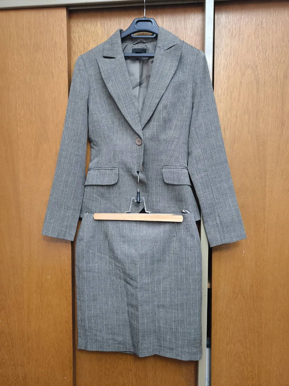 Conjunto de saco y pollera de vestir, color gris con finas rayas verticales. Ideal para un look formal o de oficina.