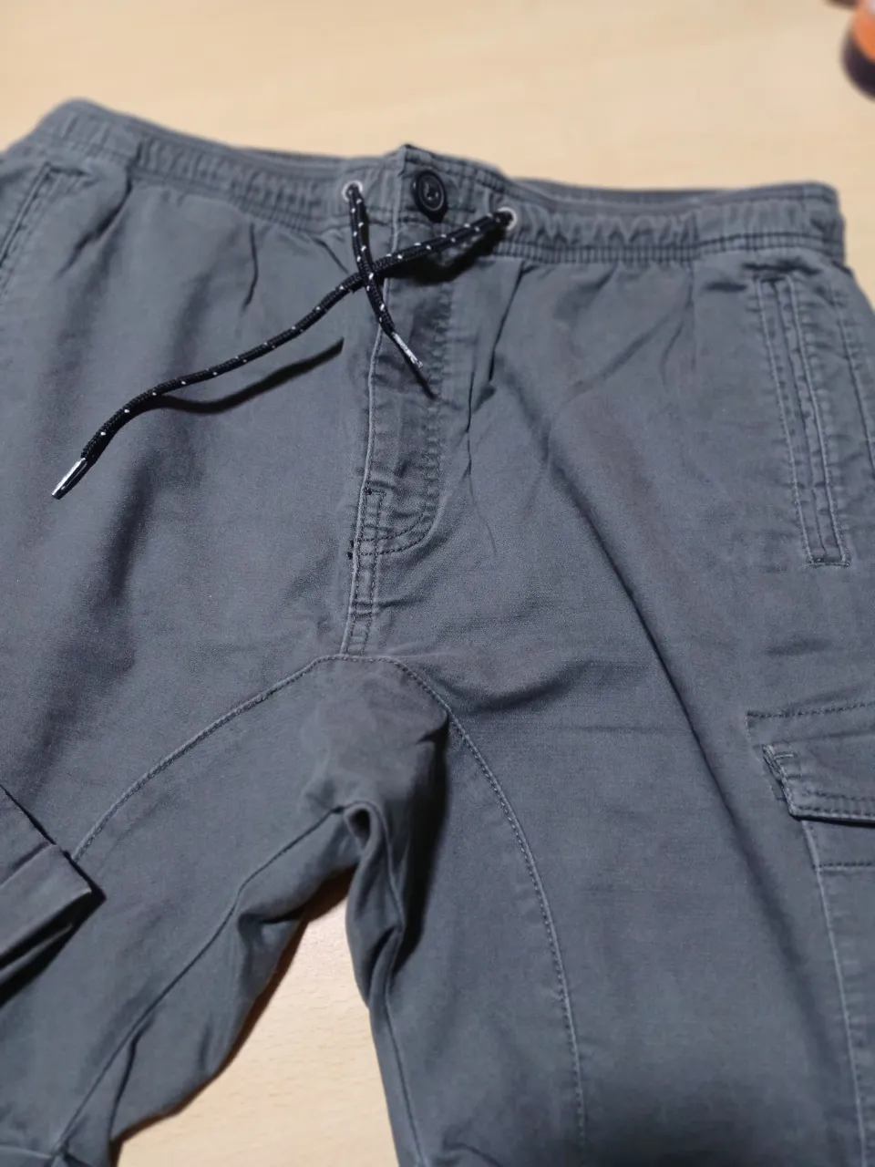 Pantalón cargo de hombre, color gris. Con cintura elastizada y cordón para ajustar. Bolsillos laterales y traseros. Ideal para un look casual y cómodo.