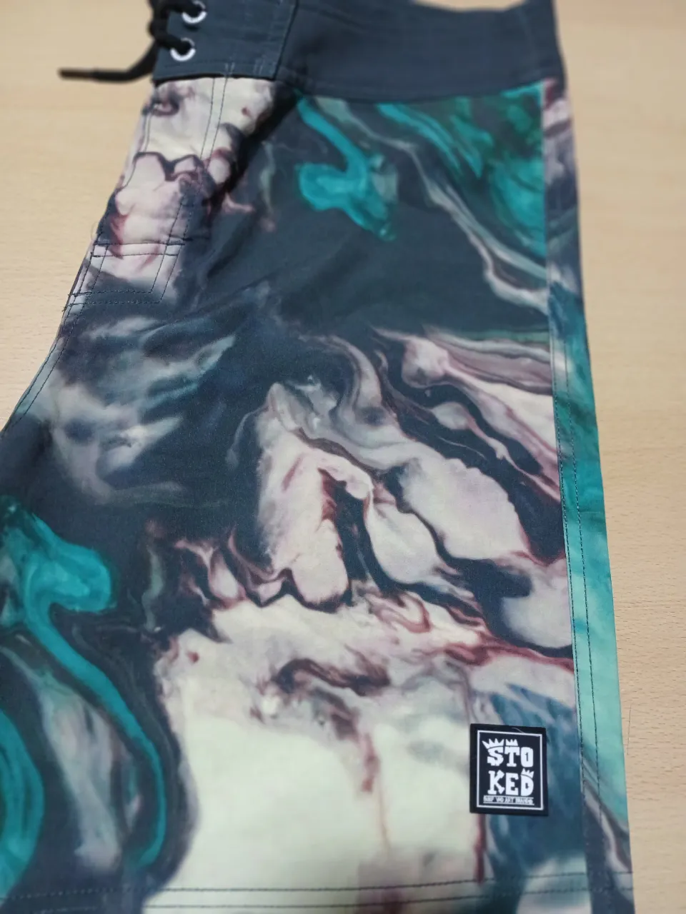 Short de baño Stoked con estampado abstracto en tonos azules, verdes y borgoña. Talle 34, ideal para la playa o pileta.